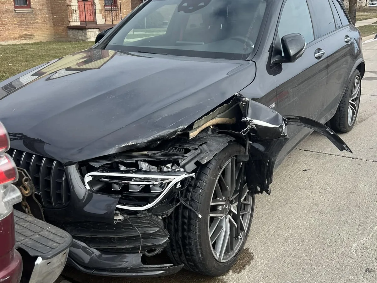 Black sedan with front end collision damage before towing