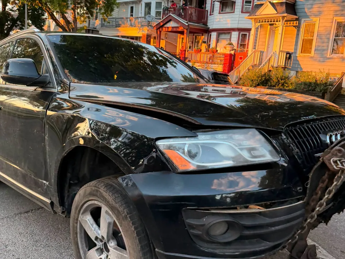Black SUV hooked to a tow truck on a city street