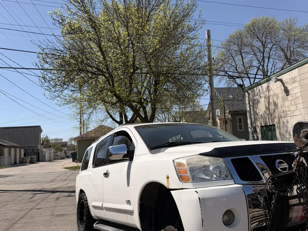 White SUV hooked to a tow truck for junk car buyback