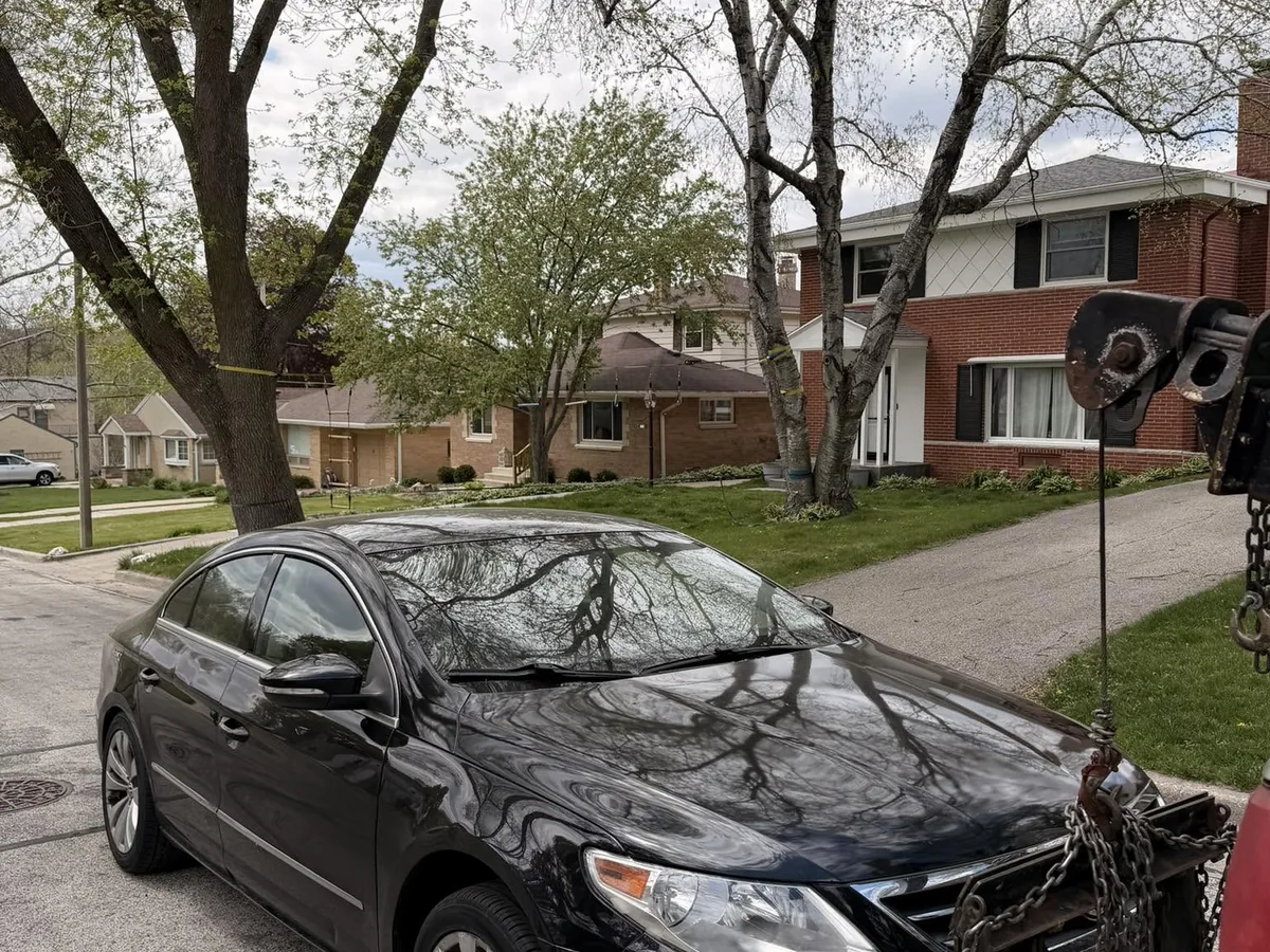 Black sedan winched onto a tow truck for junk removal
