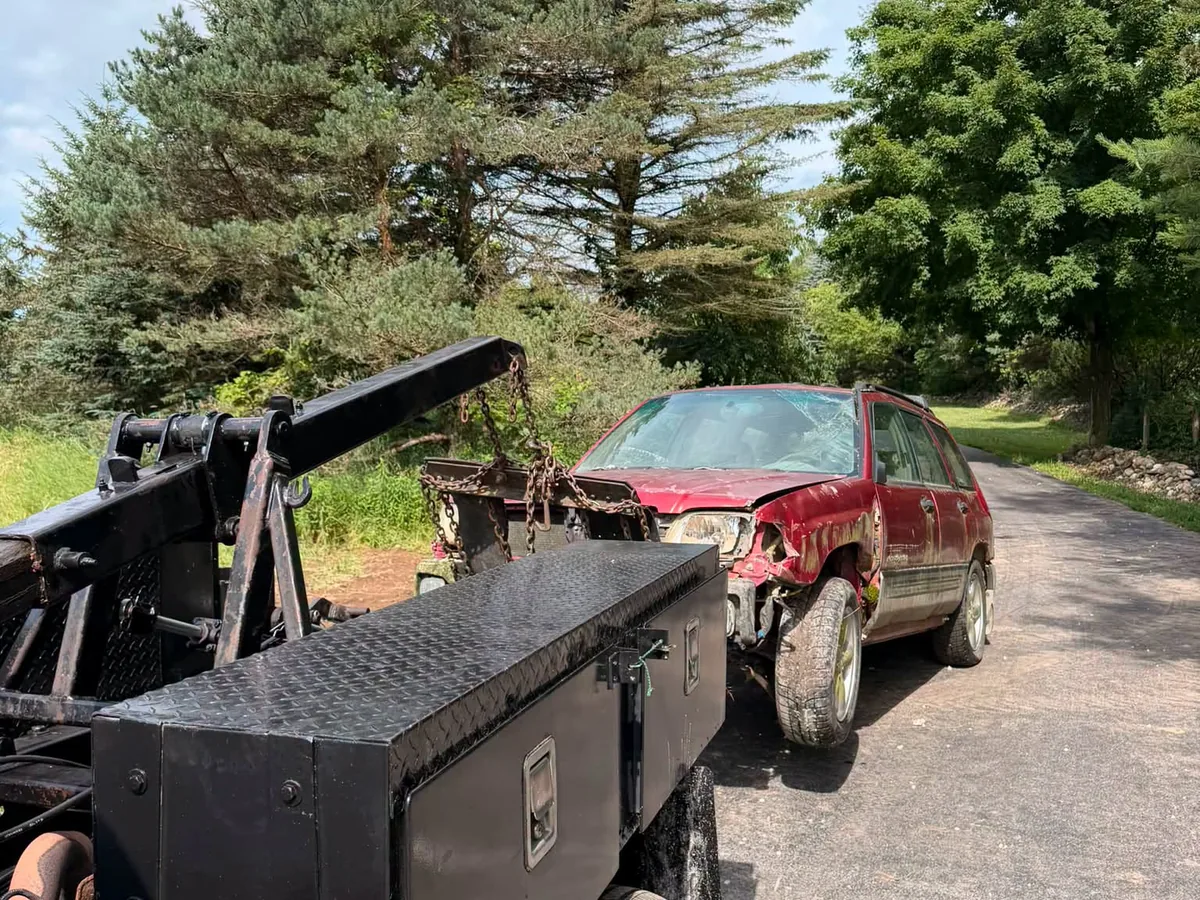 Tow truck boom hooked to a red car for removal