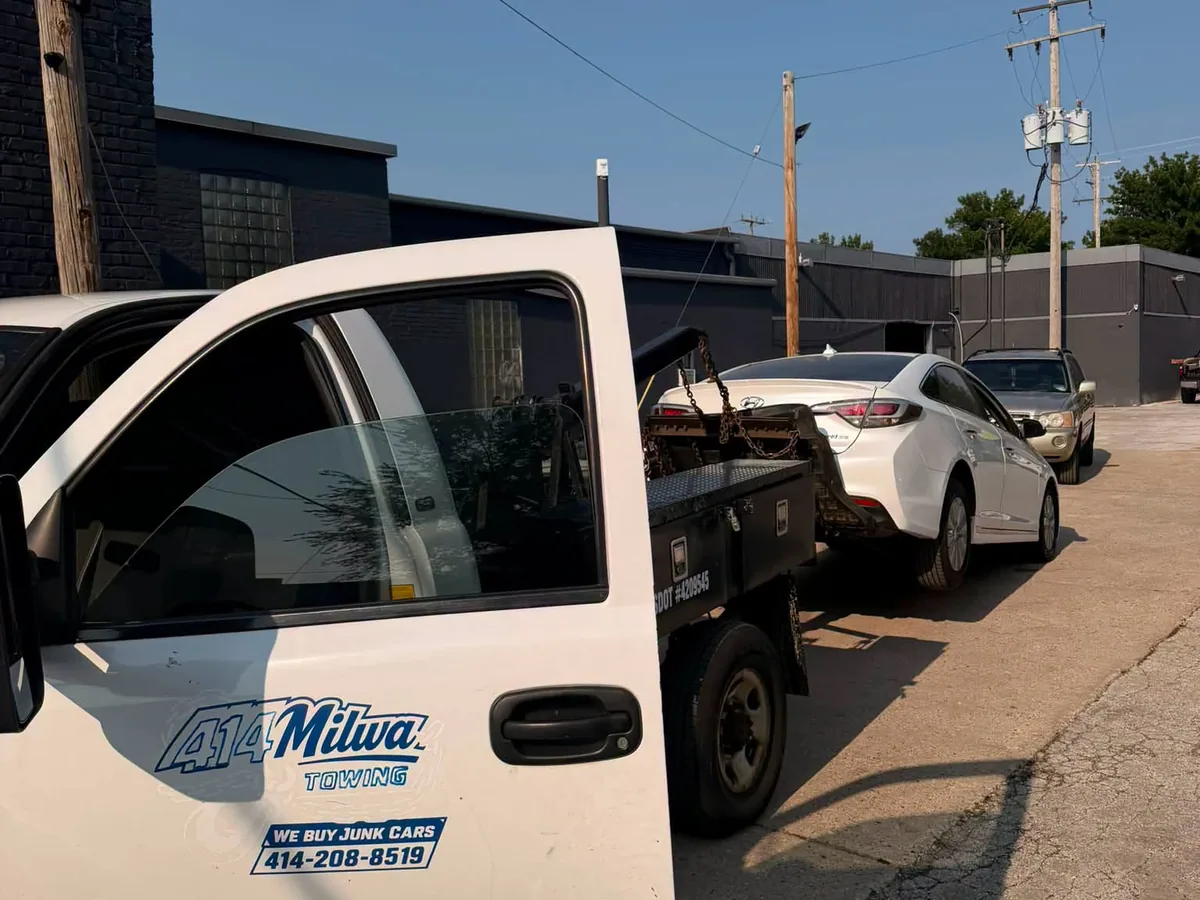 Tow truck hooked to a white car for junk car pickup