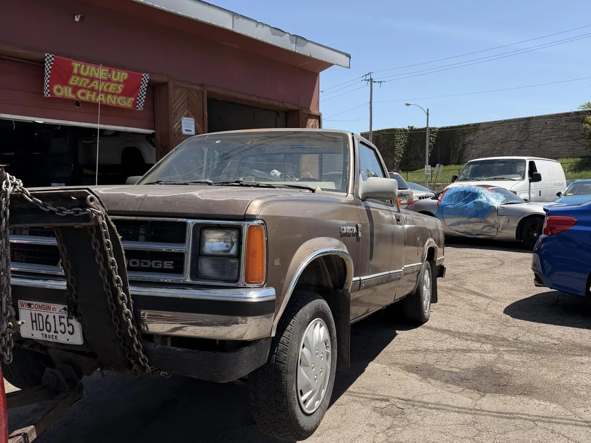 Brown pickup truck chained to a tow truck for hauling